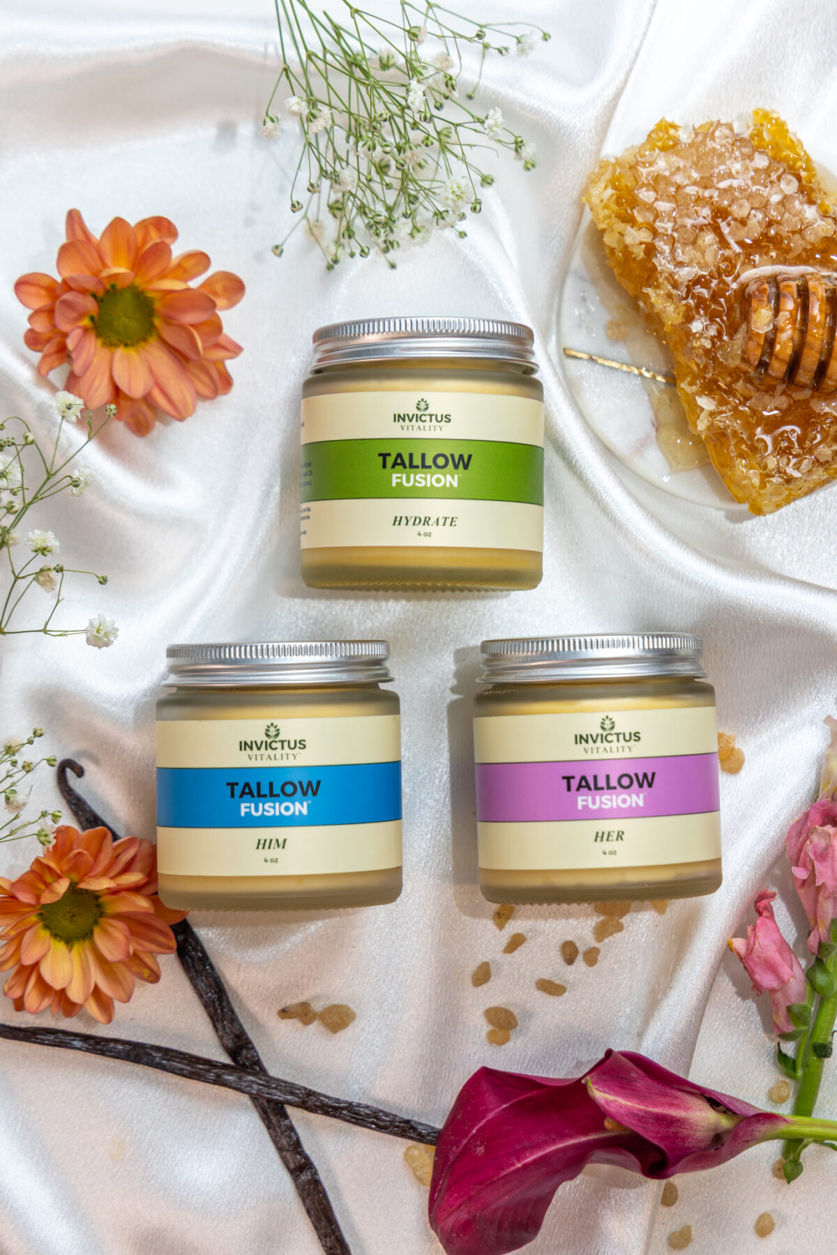 Invictus Vitality skincare products displayed on a natural slab, surrounded by raw ingredients like tallow, sea buckthorn berries, and herbs, highlighting the brand’s focus on clean, nourishing, and bioavailable skincare